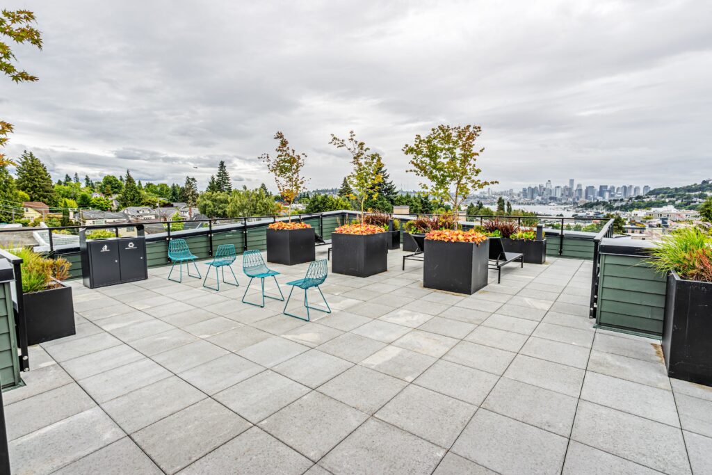Reed seattle - rooftop deck with chairs, chaiselongs and a view of skyline